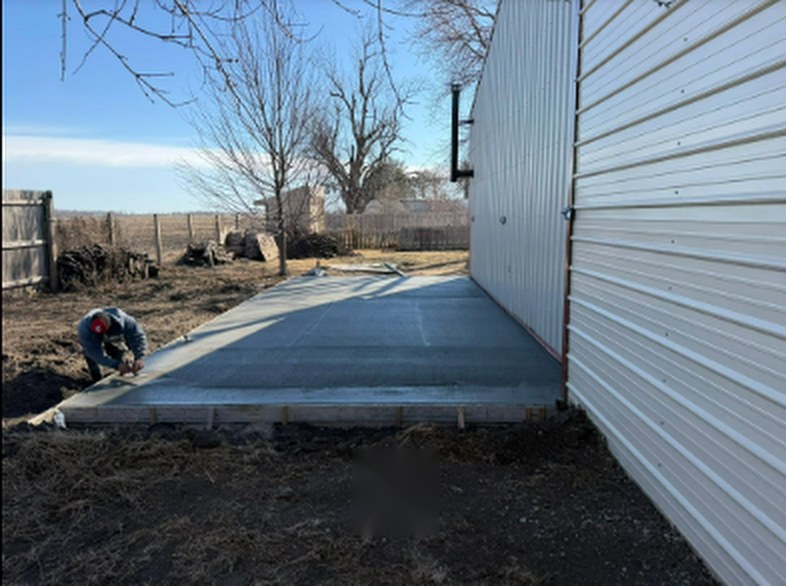 Twins Concrete crew member hand-finishing the edge of a new concrete apron in Nebraska